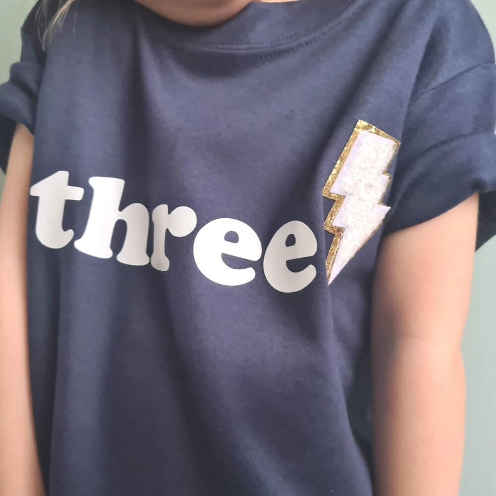 3rd birthday navy tshirt with 'three' and white / gold lightning bolt