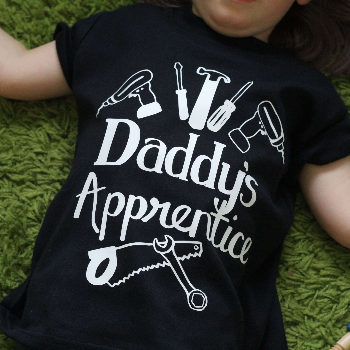 Child laying down wearing Father's day top - black tshirt with white logo