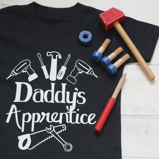 Black t-shirt with white logo 'Daddy's Apprentice' with illustrations of tools - hammer, screwdriver and drill.