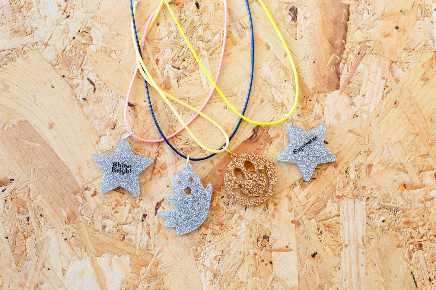 Shows all the different version of the necklaces - silver 'shine bright' star, silver ghost, silver 'superstar' star and gold smiley face.