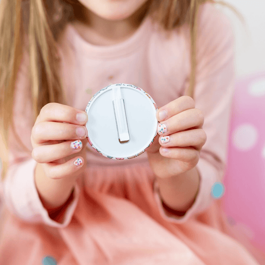 Child holding a round white object with a number one on it against a pink background