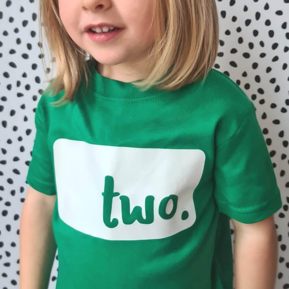 Toddler wearing a birthday age green t-shirt with logo 'two' logo from The Joyful Rebel