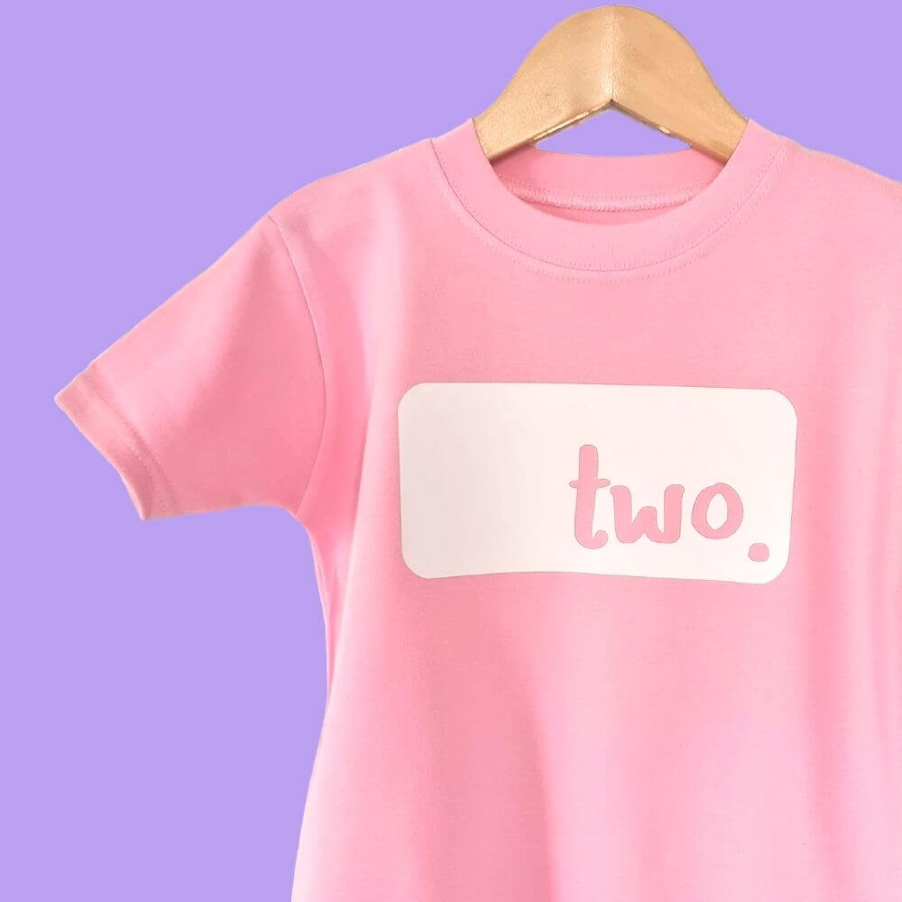 Hanging up Pale pink birthday t-shirt with white 'two logo from the The Joyful Rebel 