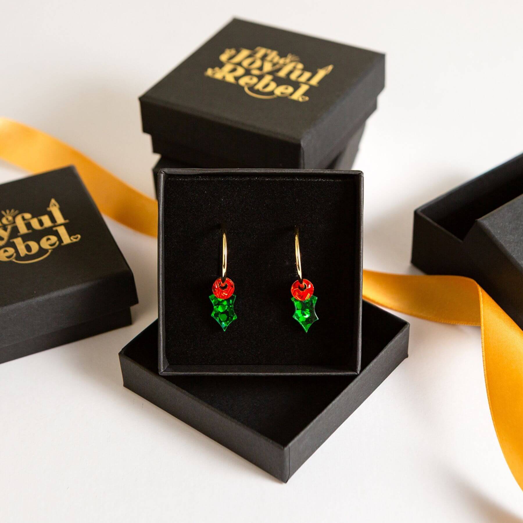 Tiny holly hoop earrings in a black jewellery gift box