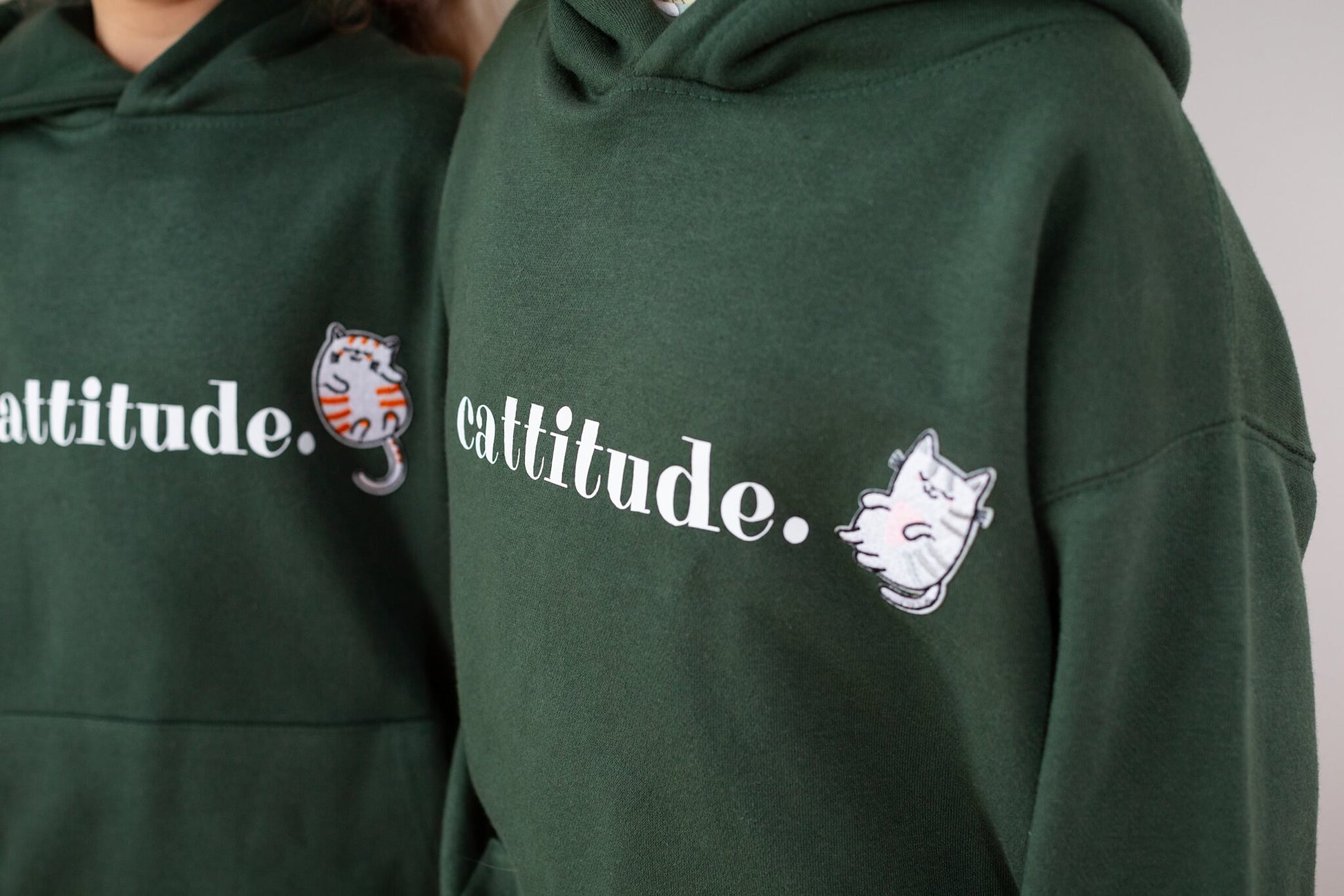 Close up of the green cattitude jumper - it show the white Cattitude text and embroidered cat