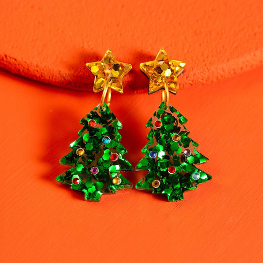 Green Christmas tree earrings with gold stars on an orange background