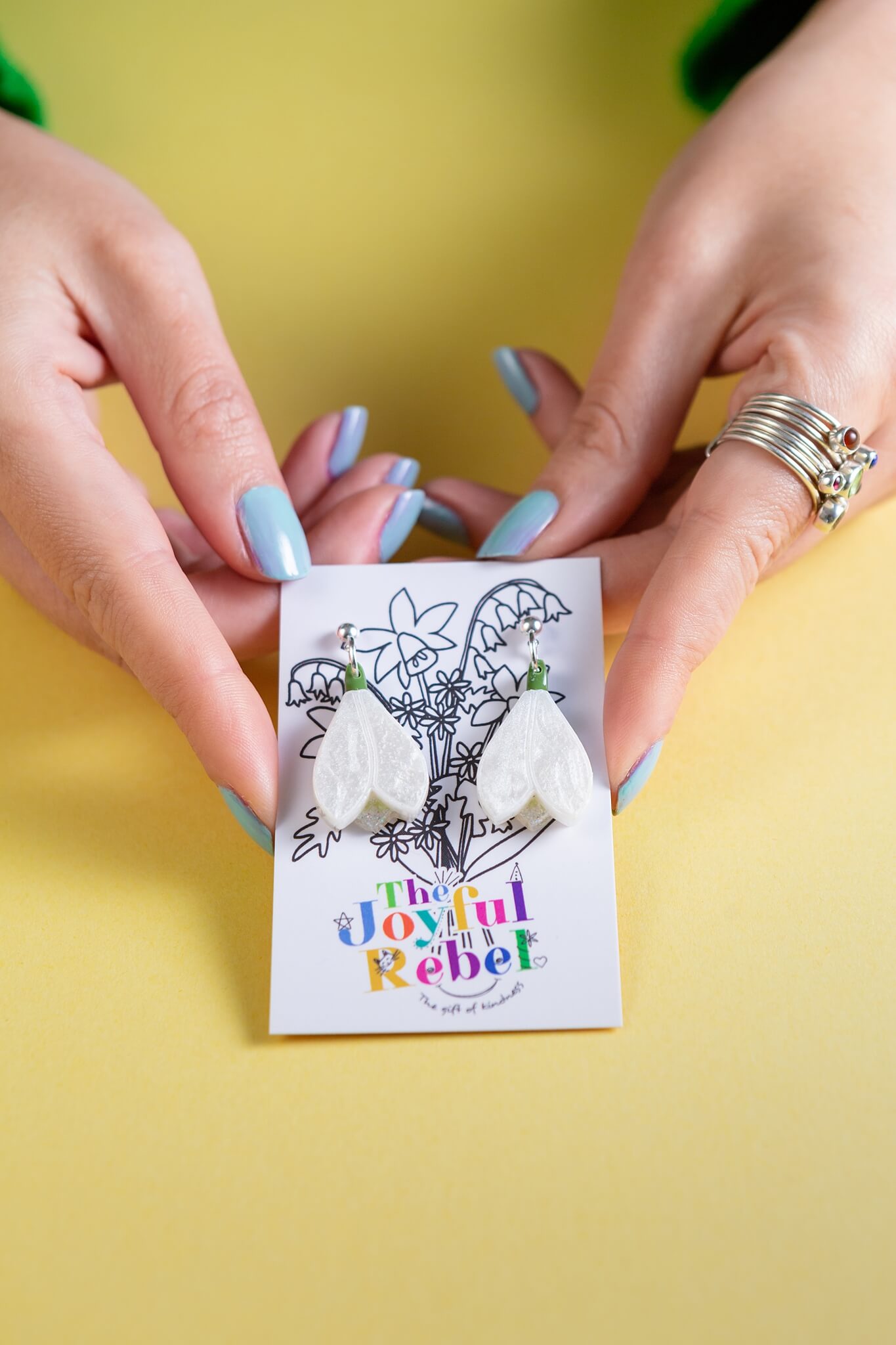 Snowdrop earrings being held in female hands by the Joyful Rebel