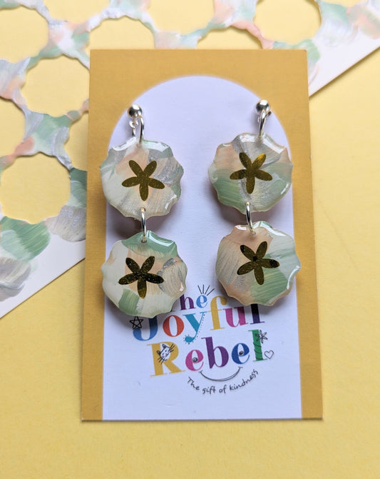 Wearable art earrings - the earrings are made pale peach, light spring green with touches of silver. In the centre of each earring is a shiny gold petals.