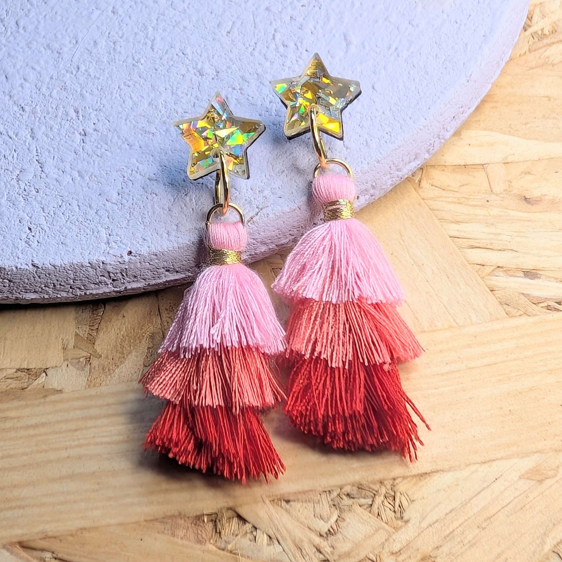 Colorful tassel earrings with star-shaped tops on a textured surface