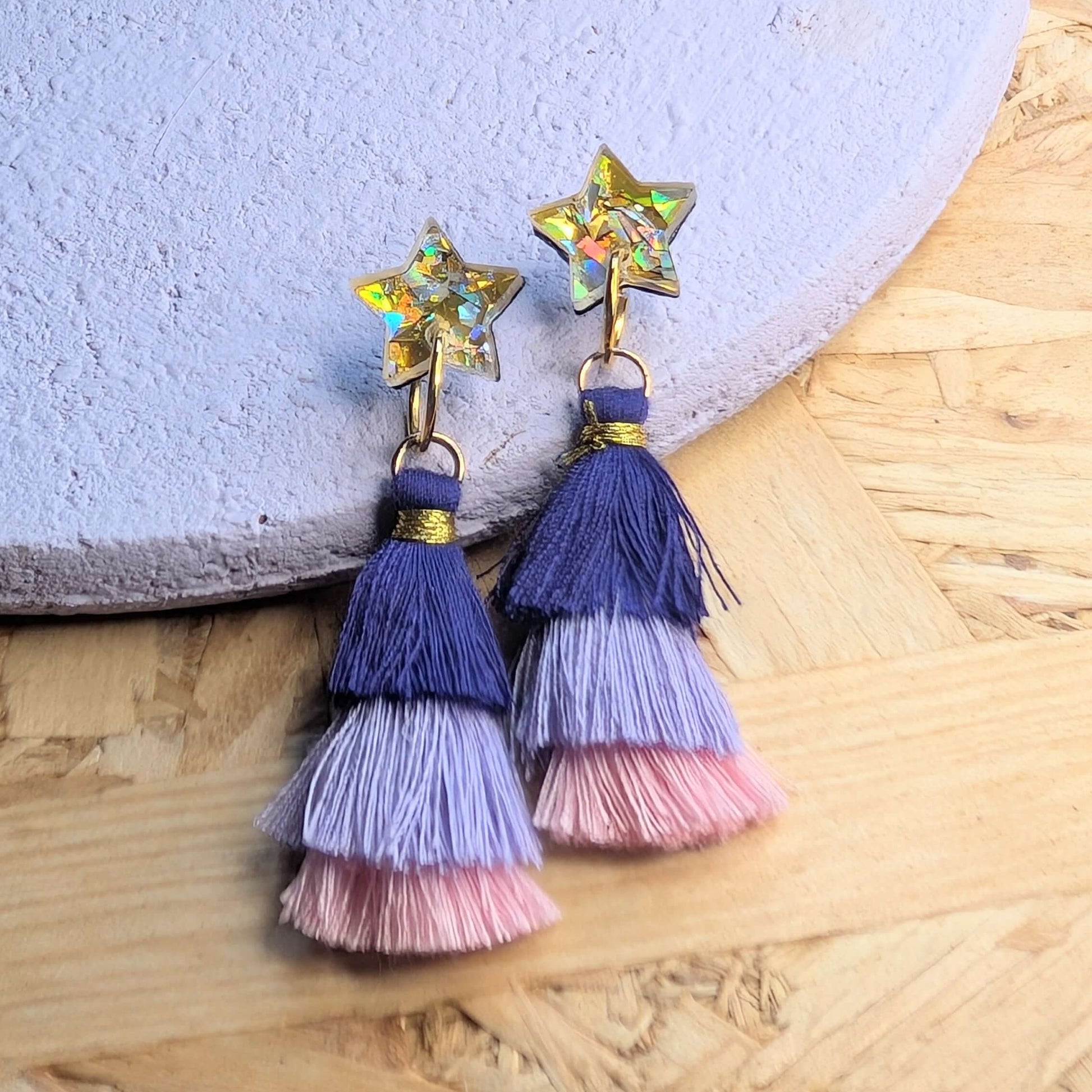 Colorful tassel earrings with star-shaped tops on a textured surface
