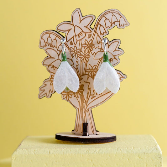 Resin Snowdrop earring hanging from a wooden drawing of bouquet, made from The Joyful Rebel.