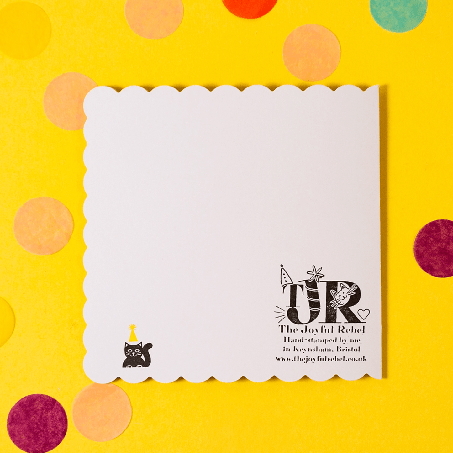 White card with black text and logo on a yellow background with colorful polka dots