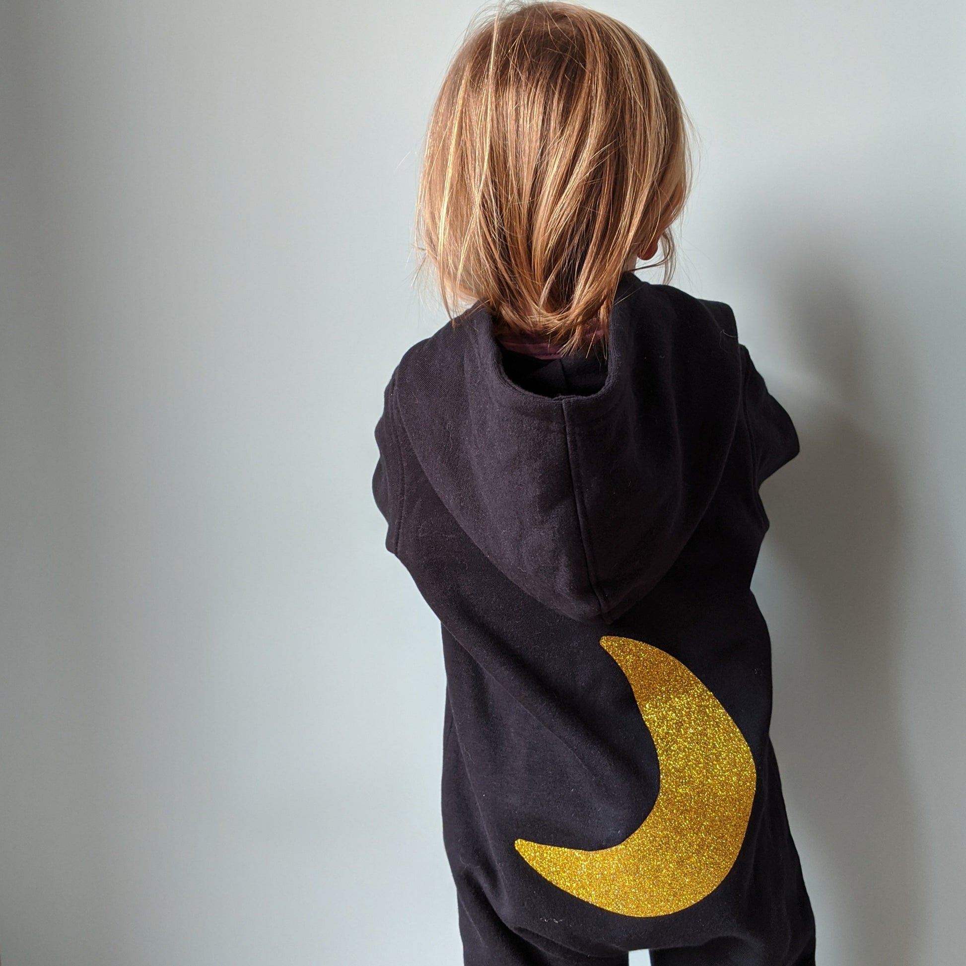 Black fleece onesie with glitter gold moon on the back